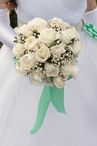 手捧白玫瑰摄影照片_新娘手捧一束美丽的白玫瑰