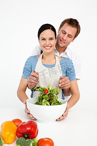 快乐的女人在厨房里和男友拌沙拉