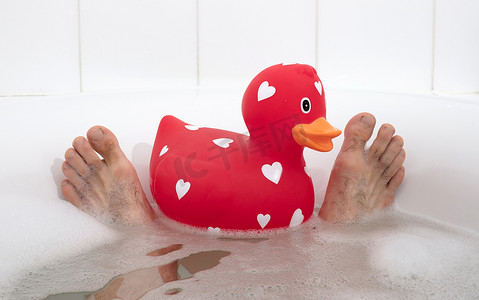 男人的脚在浴缸里，有大橡皮鸭