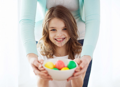 拿着彩蛋摄影照片_微笑的女孩和妈妈拿着彩蛋