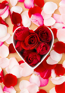 粉色心形花瓣摄影照片_心形碗内的红玫瑰，旁边有粉红色的花瓣