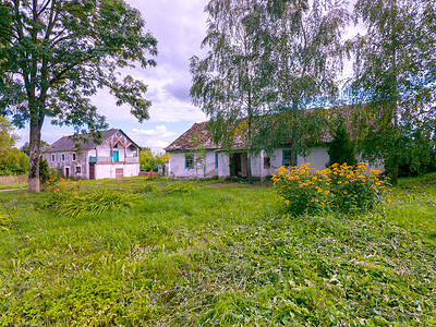 乡村的老建筑，石板屋顶长满了苔藓，院子里长满了绿草和一丛黄色美丽的花朵。