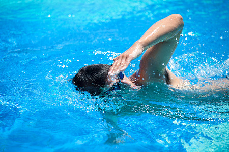 地里摄影照片_年轻人在游泳池里游泳前爬/自由泳