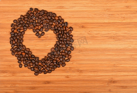 在竹木背景的心形的咖啡豆框架