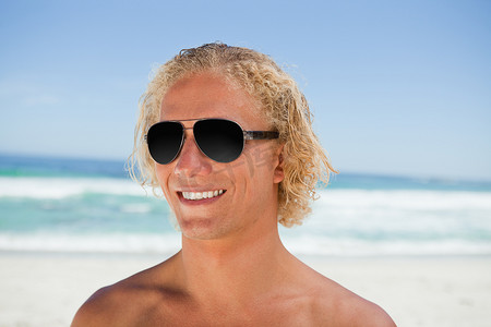 站在沙滩上戴着墨镜微笑的男人