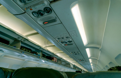 选择性地关注商用飞机上的头顶阅读灯，在头顶存放处进行模糊的头顶行李箱，门显示打开。
