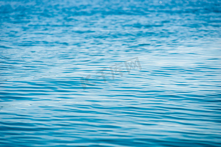 海面蓝色背景摄影照片_背景 - 平静的海面，有轻微的波纹关闭