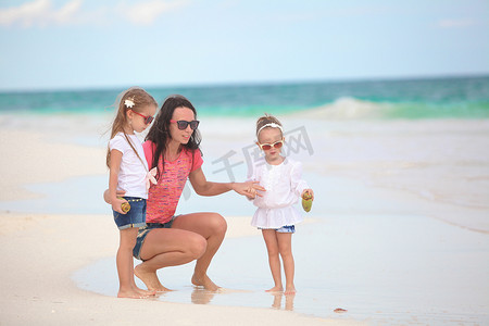 年轻的母亲和她可爱的女儿们在热带海滩享受暑假