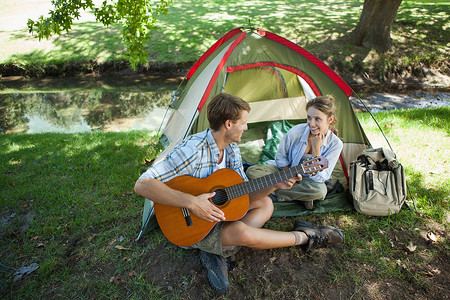 可爱的男人在野营旅行中为他的女朋友唱小夜曲