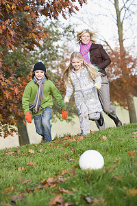 小学运动摄影照片_妈妈在公园里户外，带着两个踢足球和微笑的孩子