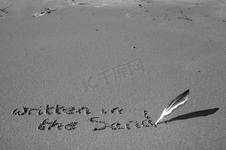 黑色毛笔摄影照片_用羽毛笔灰度写在沙子上
