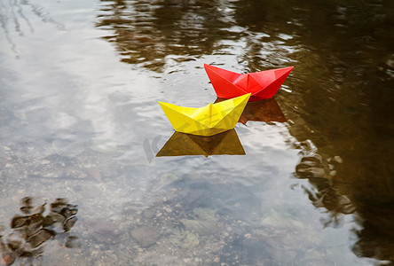 小纸船摄影照片_漂浮在溪流上的两艘五颜六色的纸船