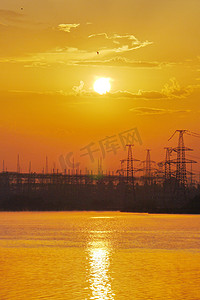 发电厂背景下水面上的黄色日落