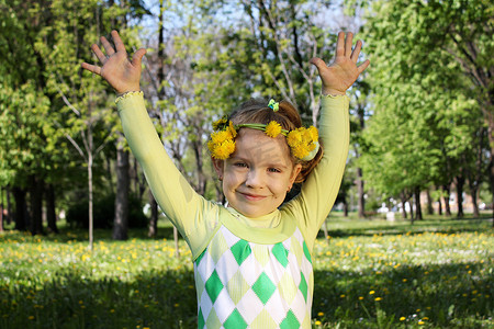 快乐的孩子在公园里举起双手，头戴花环