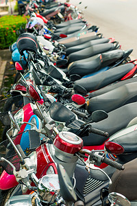 摩托车摄影照片_轻便摩托车连续停在泰国的人行道上