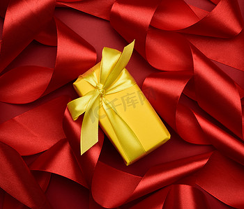 礼盒用黄色纸和红色背景上卷曲的红色丝带包装，