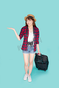 美丽的年轻亚洲女性微笑着带着行李旅行夏季旅行，并在假期为国外展示一些东西，亚洲女孩拿着相机走路，拉着手提箱在假期旅行。