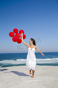 幸福感摄影照片_拿着红色气球奔跑的漂亮女孩