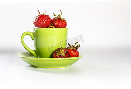新鲜多汁的草莓在绿色杯子和碟子上隔离