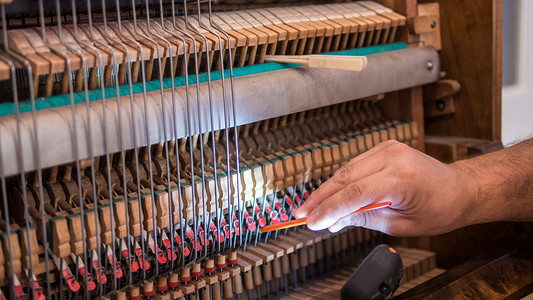 专业工人修理和调音一架旧英国刺刀钢琴的手的特写镜头
