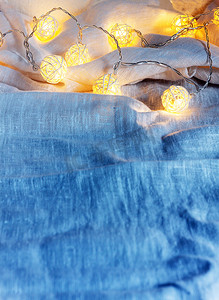 织物褶皱摄影照片_蓝色织物褶皱上带灯的花环背景