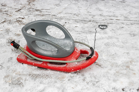 路上雪地上的红灰色塑料雪橇