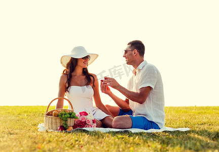 小青柑礼盒摄影照片_带着红色小礼盒在野餐时微笑的情侣