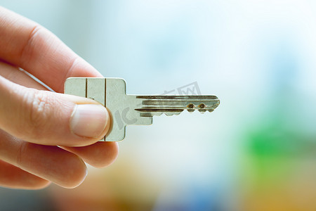 居住空间摄影照片_搬进新家：拿着钥匙的手的特写。