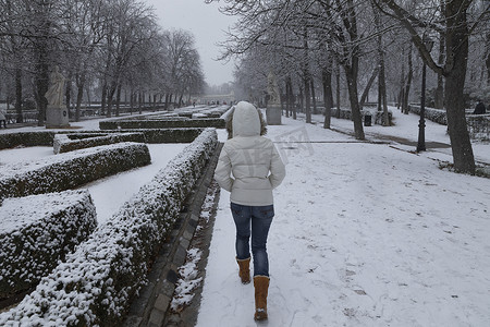 年轻女孩在马德里丽池公园享受下雪天。