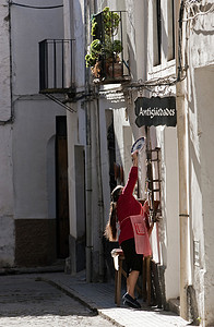 西班牙安达卢西亚哈恩省乌韦达一家古董店门上挂着陶瓷盘子的女人