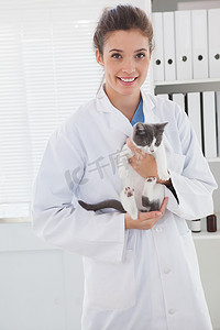 一只可爱的小猫摄影照片_微笑的兽医怀里抱着一只可爱的小猫