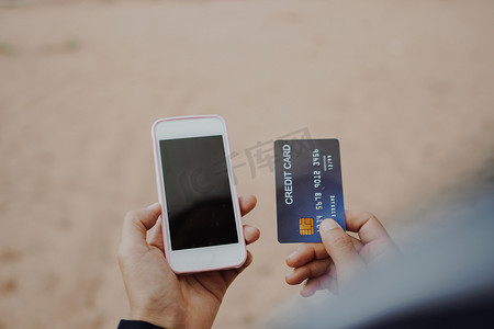 购物app摄影照片_妇女手持信用卡并使用移动智能手机进行网上购物或报告丢失的卡、欺诈交易。