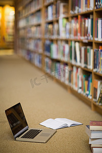图书馆地板上的笔记本电脑和书籍