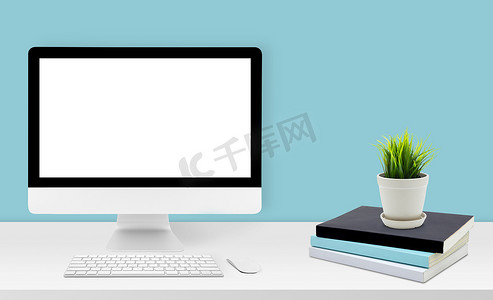 模型台式计算机在办公室的办公桌上显示空白屏幕，工作区与模型计算机屏幕为空，键盘、鼠标、植物和复制空间在家里的桌子上，业务演示概念。
