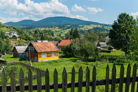 一个乡村山村背景的旧木栅栏，那里有漂亮的小房子