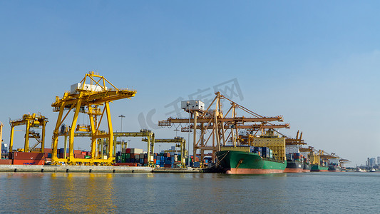 供应链脱链摄影照片_集装箱货船和货机在日出时在造船厂工作起重机桥的物流运输、物流进出口和运输行业背景