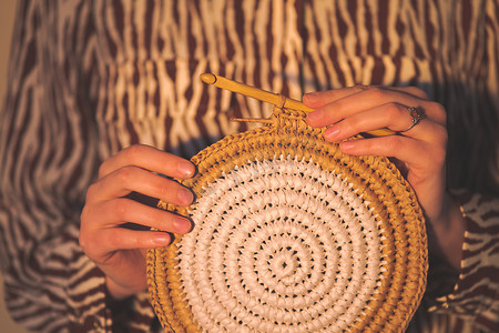 女性手中的圆形拉菲草钩针编织 panno。