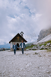 一对夫妇在雾蒙蒙的天气里在意大利多洛米蒂山徒步旅行，可以欣赏到意大利多洛米蒂山 Tre Cime 峰的壮丽景色