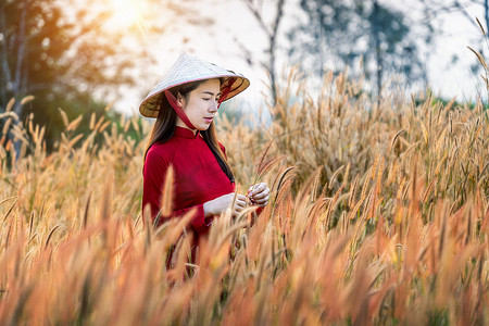 连衣裙亚洲女性摄影照片_穿着非洲喷泉花田传统越南文化的亚洲女性。