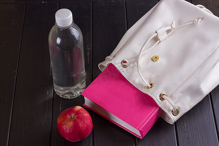 白色皮革背包、粉色书籍、瓶装水