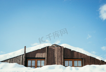 屋顶有窗户和雪的现代木屋，蓝天有文字空间
