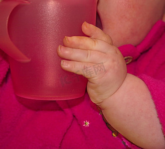 婴儿胖乎乎的手拿着一个大杯子