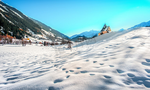 铁证如山摄影照片_冬季早晨全景教堂的山景、如画的雪脚印