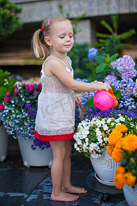 漂亮的小女孩用喷壶浇花