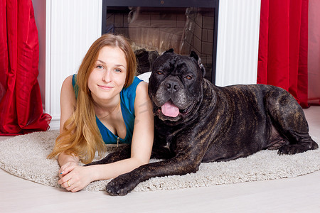 女孩和他的狗 Cane Corso 在壁炉旁的家中