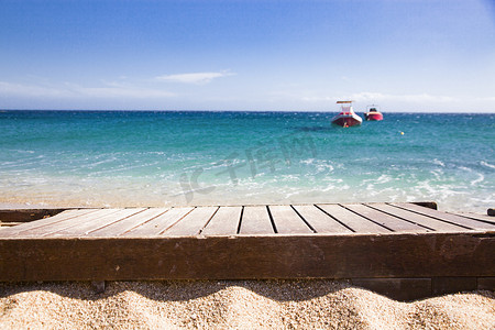 背景中沙子和蓝色大海中的木板