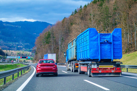 红色汽车在高速公路上超车蓝色卡车