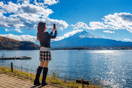 河口摄影照片_女人用手机在日本河口湖富士山拍照。