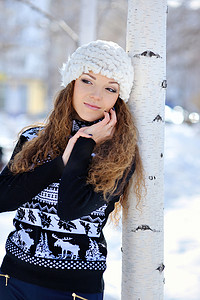 条纹毛衣摄影照片_身穿条纹毛衣和白色雪地靴的年轻黑发女孩