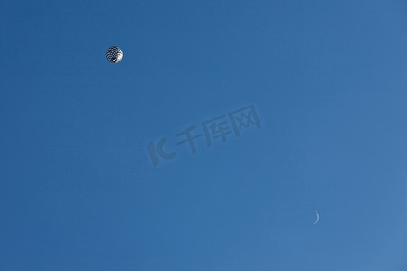 飞行中的黑白气球和从下方看到的月亮
